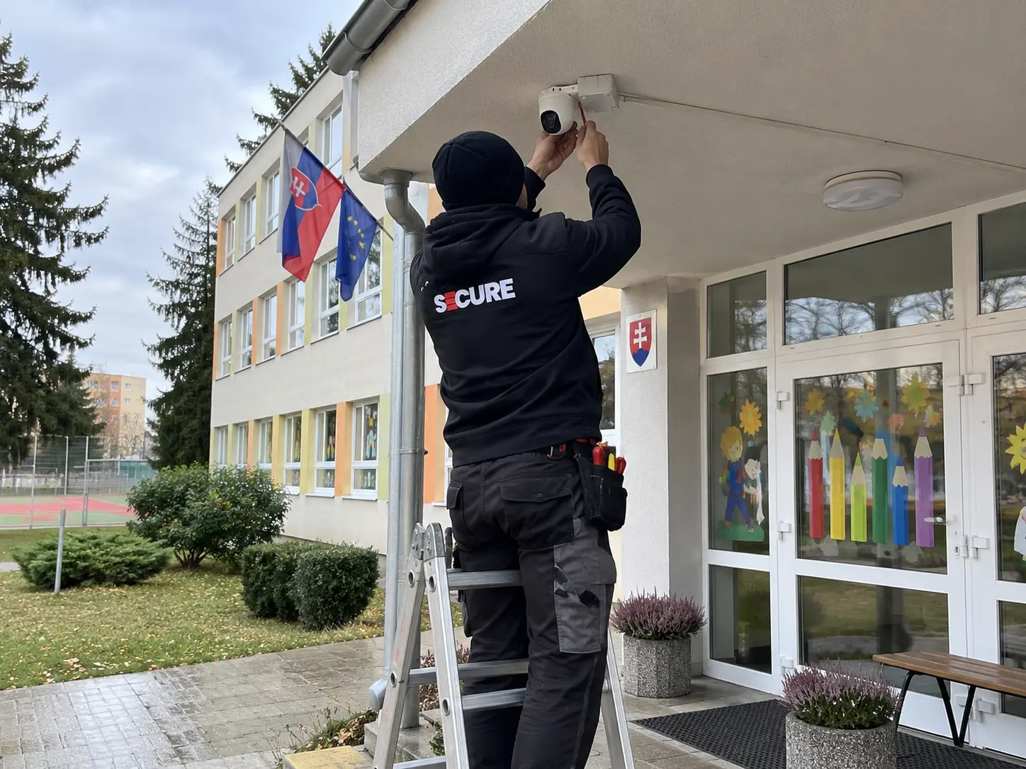 Technik SECURE montuje kameru nad hlavným vchodom do školy